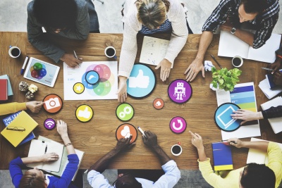 social media marketing team strategising around work desk using vector social media icons